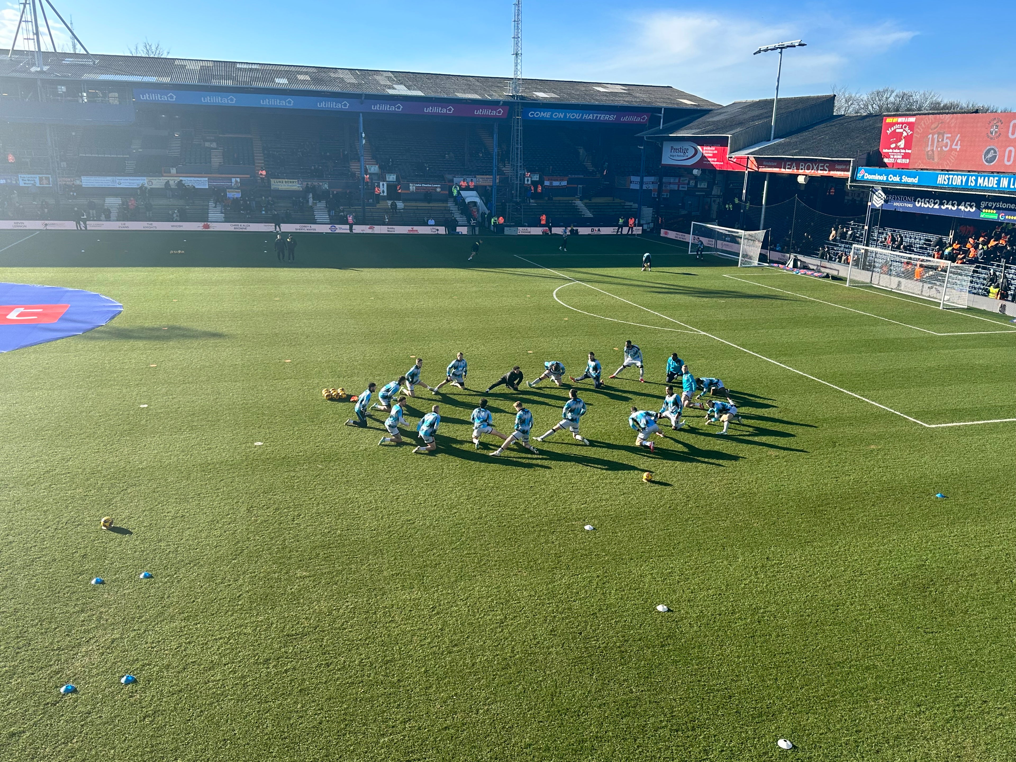 Soccer players on a field with a stadium in the background